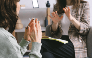 Two women talking to each other using hand gestures.