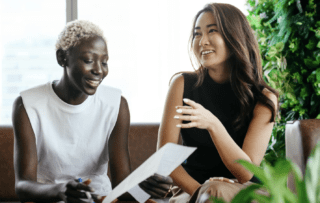 Two women talking to each other happily being aware of each others ideas.