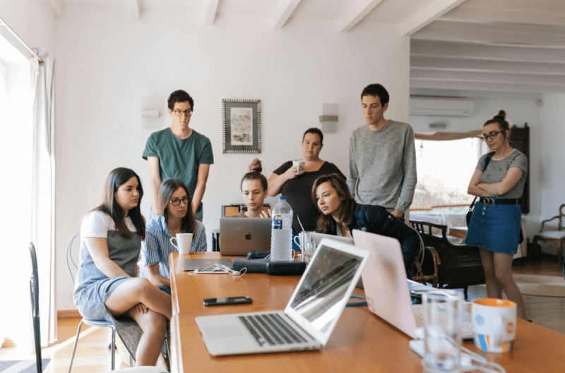 A workplace with a group of people gathered around. 