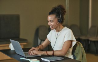 A Woman with Curly Hair Working while Smiling.