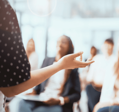 A person lecturing a group of seated businesspeople.