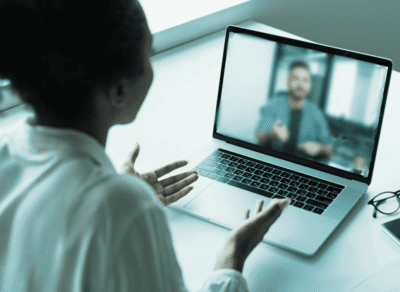 A woman speaks to a man on a video call on her laptop.