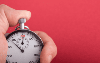 Image of a hand on a stop watch to measure time and speed.