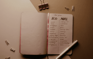 A photo of a note book with two columns on the left side it says 'less' and on the right side it says 'more', with a list underneath each side.